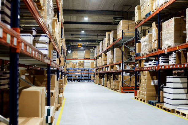 istock Empty warehouse, view down the asile with shelves and boxes. 1148210544