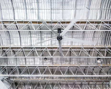 Large ceiling fan on the metal frame of the modern factory for ventilation.