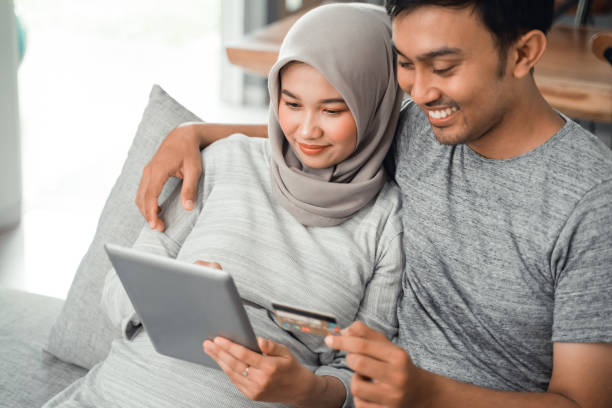 muslim couple buy and do payment using credit card asian muslim couple buy and do payment using credit card while online shopping on market place malay couple stock pictures, royalty-free photos & images
