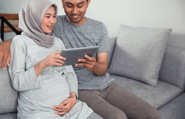 schwangere frau mit tablet-pc mit ehemann - standing digital tablet couple love stock-fotos und bilder