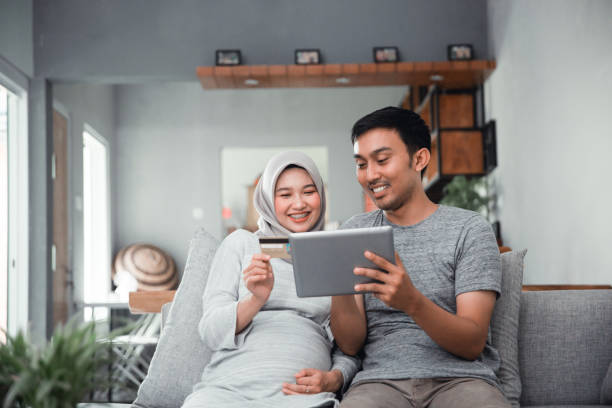 muslim couple buy and do payment using credit card asian muslim couple buy and do payment using credit card while online shopping on market place happy malay couple stock pictures, royalty-free photos & images