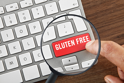 Looking down on a magnifying glass with hand clicking on an enter key quoting ”Gluten free\