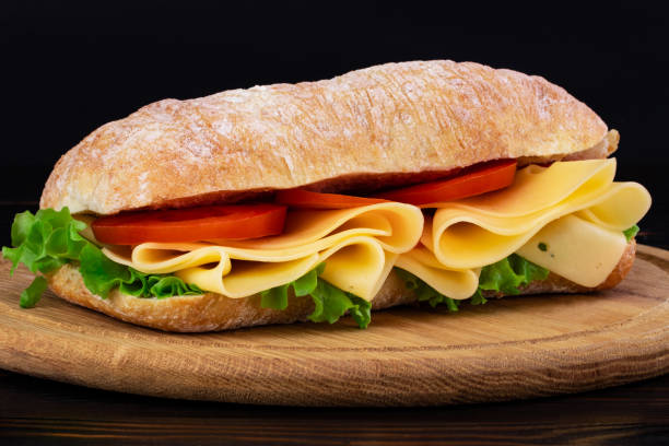 istock Ciabatta sandwich with lettuce , prosciutto and  cheese on wooden board 1148216680