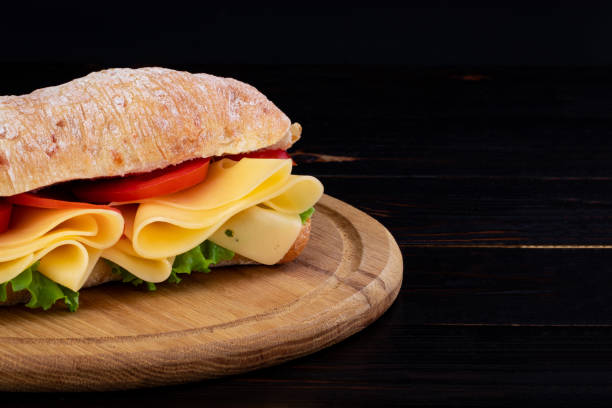 istock Ciabatta sandwich with lettuce , prosciutto and  cheese on wooden board with copy space 1148216703