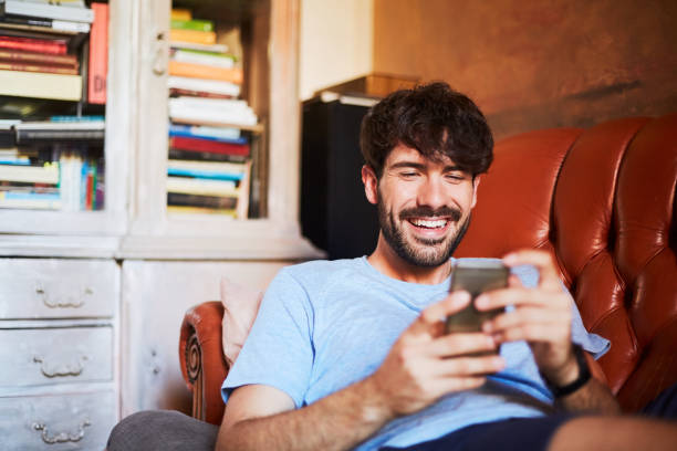 istock One man relaxing at home texting with a smart phone. 1148216888