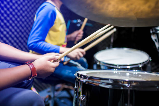 hands of teacher with wooden drumsticks guiding boy in drum learning tutorial in recording