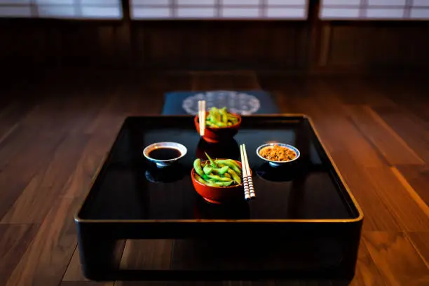 Traditional japanese machiya house or ryokan restaurant with black lacquered wood table and edamame food with natto and soy sauce