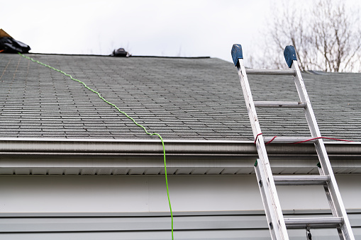 Primer cierre de casa durante el día sobre garaje con color gris casa unifamiliar y tejas de techo y escalera durante la reparación photo