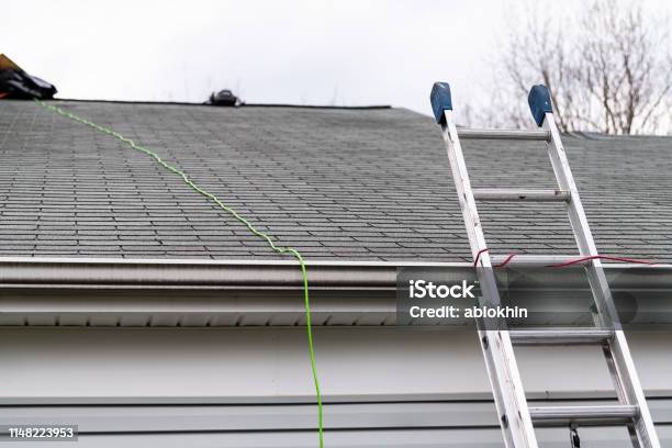 Front Closeup Of House During Day Over Garage With Gray Color Single Family Home And Roof Shingles And Ladder During Repair Stock Photo - Download Image Now