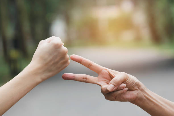 istock closeup young women are playing rock paper scissors. 1148225544
