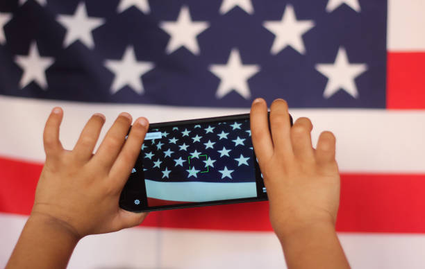 concepto de patriotismo, 4 de julio, día de la independencia y nacional. niño con un smartphone fotografiando la bandera americana. - child patriotism saluting flag fotografías e imágenes de stock