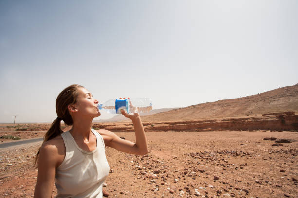 istock woman in the desert who drinks water 1148231142