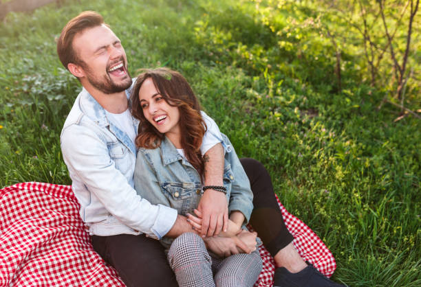 istock Laughing couple sitting on green grass 1148231356