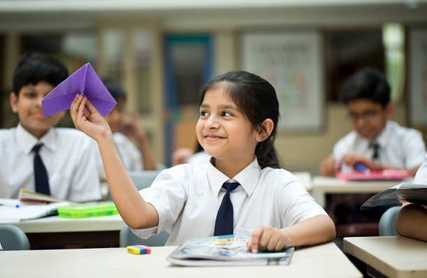 istock Schoolgirl throwing paper airplane in classroom 1148232211