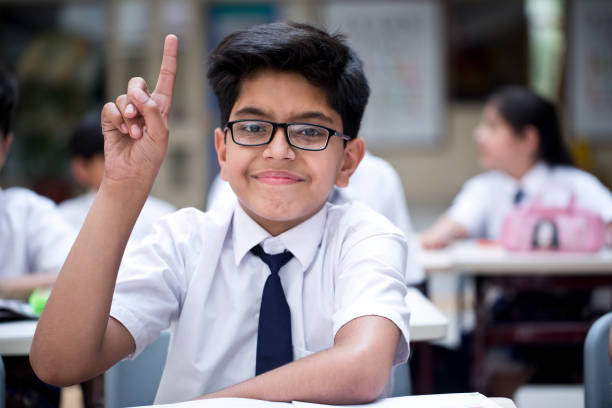 Schoolboy raising hand in classroom