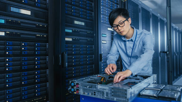 dans le centre de données moderne: technicien informatique travaillant avec des racks de serveurs, sur un chariot pushcart divers équipements nécessaires pour l’installation de nouveaux disques durs, la maintenance matérielle et les diagnostics. - network server data center installing photos et images de collection