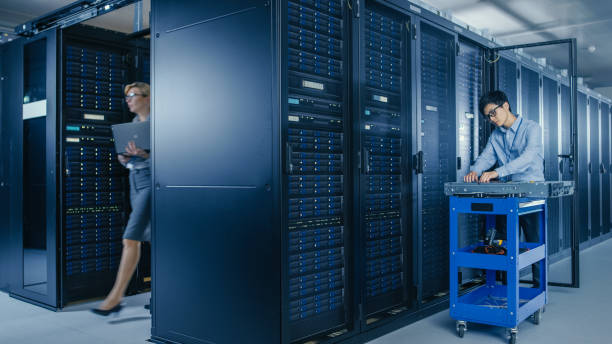 istock In the Modern Data Center: Team of IT Technicians Working with Server Racks, Man with Pushcart Changes Faulty Hard Drives, Doing Hardware Maintenance and Diagnostics. 1148233815