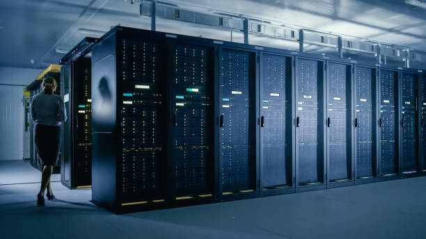 istock In Data Center: Female IT Technician Walks Alongside Row of Server Racks, Uses Laptop Computer to Run Maintenance Diagnostics so that Mainframe Works at Optimal Functioning Level. 1148233880