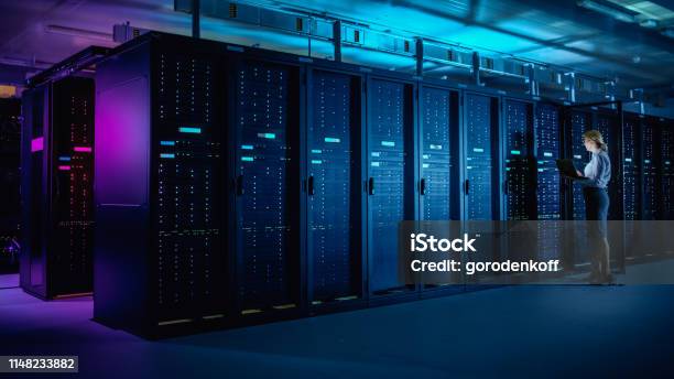 In Data Center It Technician Running Maintenance Programme On Laptop Controls Operational Server Rack Optimal Functioning Modern Hightech Telecommunications Operational Data Center In Neon Lights Stock Photo - Download Image Now