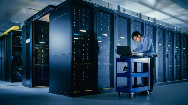 istock In the Modern Data Center: IT Engineer Doing Maintenance and Diagnostics. Pushes Cart alongside Server Racks, Ready to Install New Hardware for Planned System Update, Equipment Replacement. 1148233887