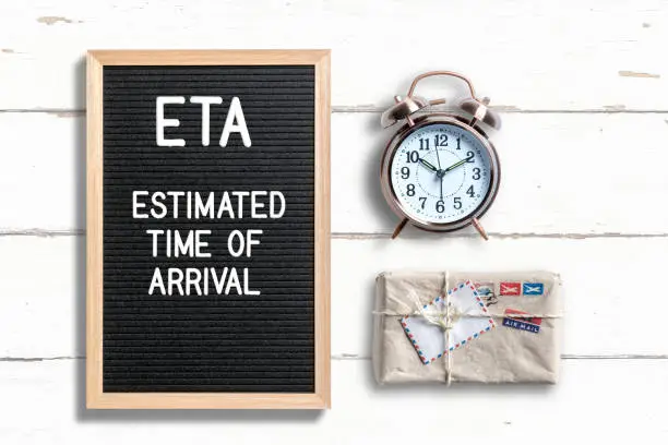 acronym ETA on a letterboard with a note explaining it as "Estimated Time of Arrival" on wooden background