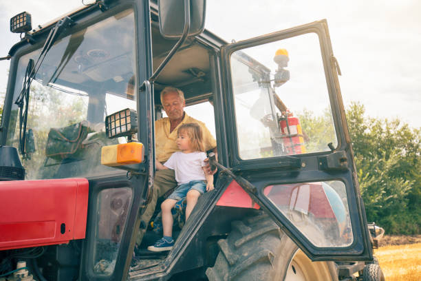 istock Child and grandfather on tractor 1148235327