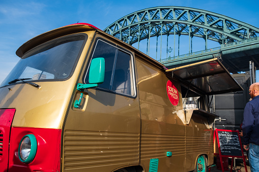 Newcastle, United Kingdom - February 23, 2019: A rennovated classic van is used as a portable canteen serving pizza at Gateshead, Newcastle with Tyne Bridge in the background