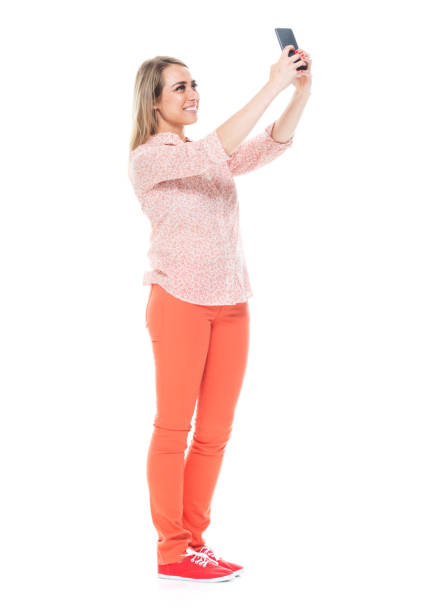 istock Good looking white female standing on white background - taking a selfie 1148235628