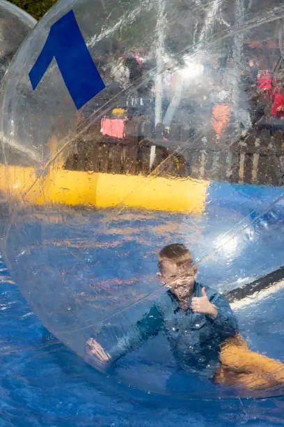 Photo of Water or aqua zorbing. Children play inside the inflatable transparent ball floating in swimming pool. Water walking or zorbing very popular fun activity and suitable for all ages.