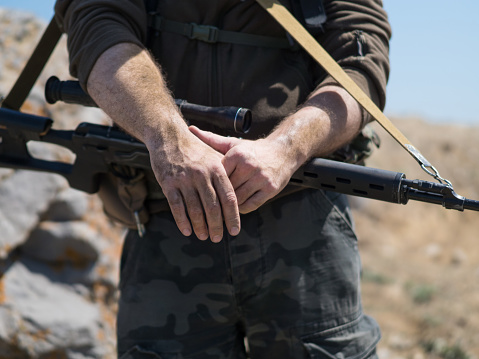 Close up view of a sniper's hands. War conflict. Terrorist.