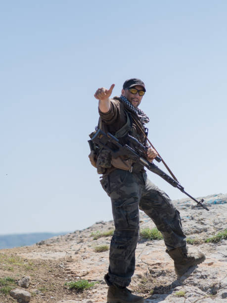 istock sniper standing with arms and looking to camera and keep thumbs up. Armed conflict. 1148239848