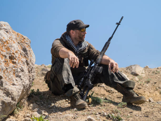 istock sniper sitting on the ground with arms and looking to the side. 1148240366