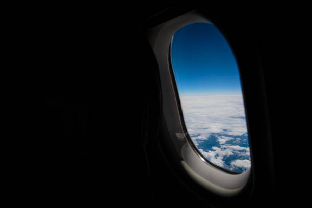 A passenger is looking at scenery through a window of an airplane.