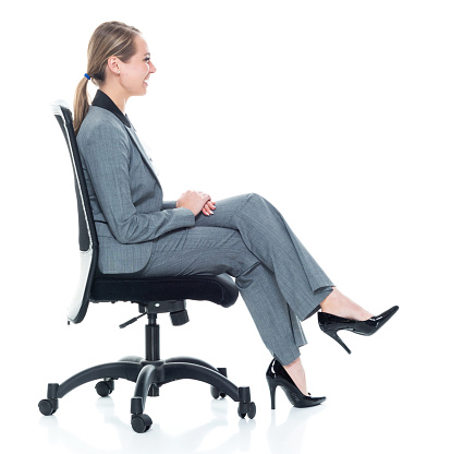 Content young businesswoman sitting on an office chair smiling at camera