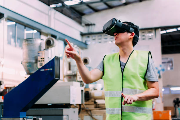 Industrial factory worker wearing VR goggle touching in virtual reality world inside factory stock photo