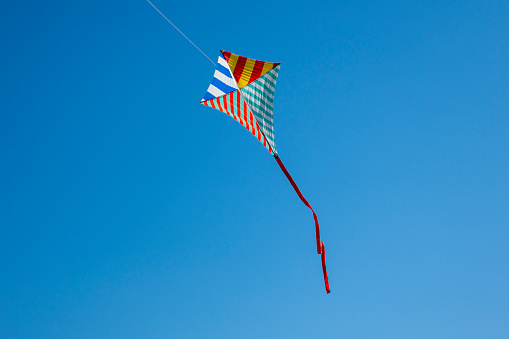 Colorful kite flying with waving red bow
