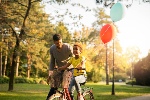 маленькая девочка учится ездить на велосипеде с помощью отца. счастливого семейного времени. - park and ride стоковые фото и изображения