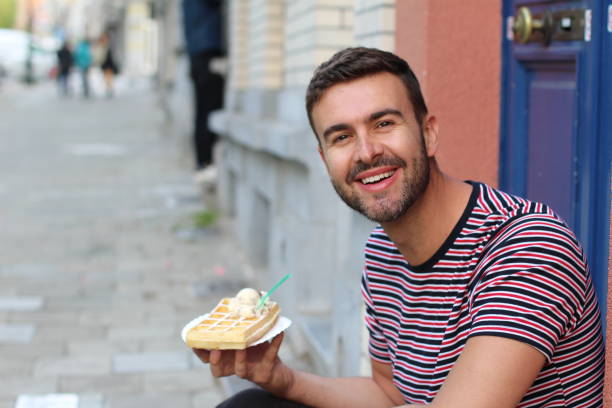 un tipo guapo comiendo un waffle en bruselas, bélgica - brussels waffle belgian waffle people fotografías e imágenes de stock
