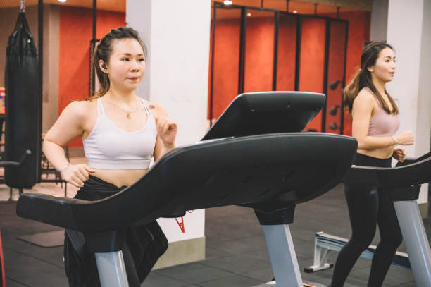 2 asian chinese female running on tread mill in gym - run of the mill imagens e fotografias de stock