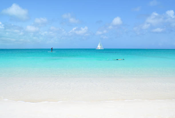 Water Sports in the Turks and Caicos Islands Looking out at Grace Bay in the Turks and Caicos Islands where there is a paddle boarder, snorkeler and sailboats. Grace Bay stock pictures, royalty-free photos & images