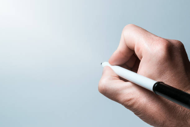 Close-up of a human hand writing on blank space with a black marker