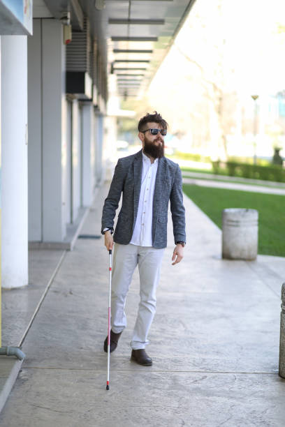 istock Blind and bearded man with a walking stick on the street 1148252076