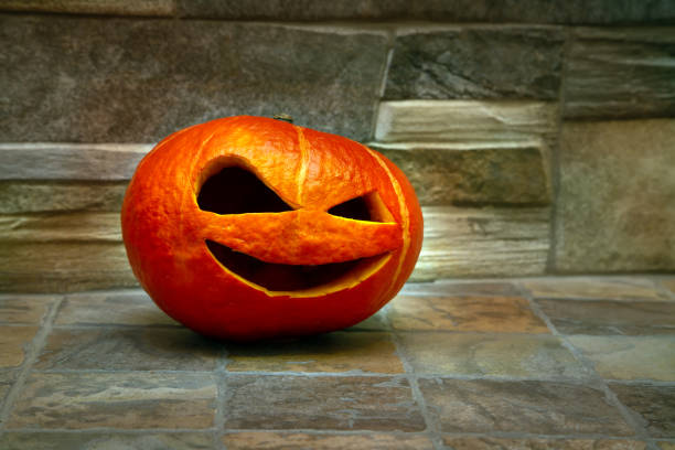 istock Halloween pumpkin stands on a stone floor against a stone wall. Jack o` lantern 1148254037