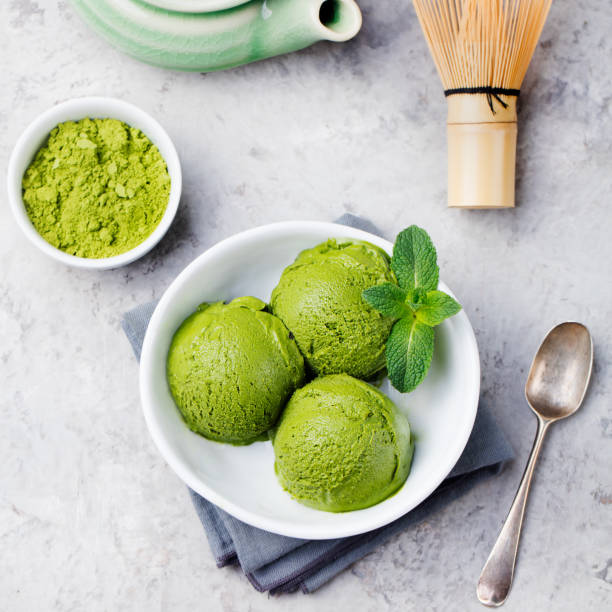 istock Green tea matcha ice cream scoop in white bowl. Grey stone background. Top view. 1148257186