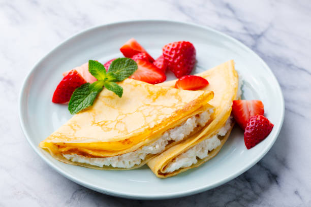 crepes, dünne pfannkuchen mit frischkäse, ricotta und frische erdbeeren. marmorhintergrund. - pancake blini russian cuisine french cuisine stock-fotos und bilder