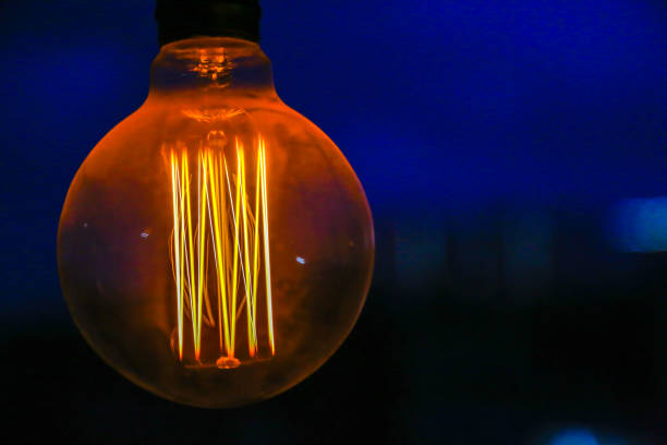 istock Edison's lamp hangs included. Lamp closeup shines on a blue background 1148259120