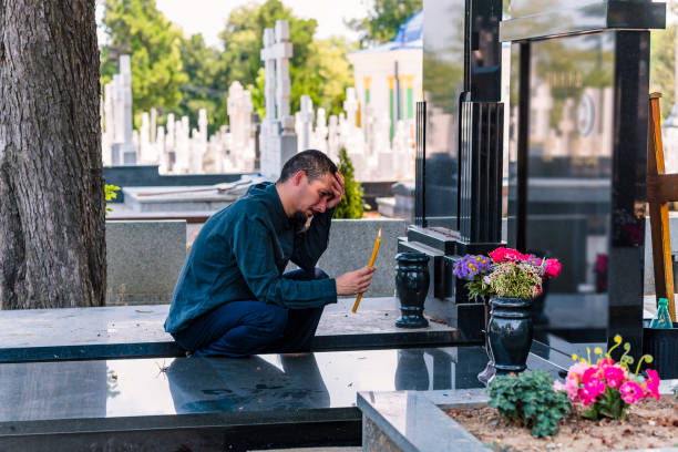 emotional gestresst mann mit einer kerze auf dem friedhof - spooky cemetery single flower flower stock-fotos und bilder