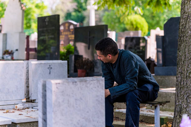 istock Sad and Emotionally Broken Man Sitting at the Cemetery 1148260050