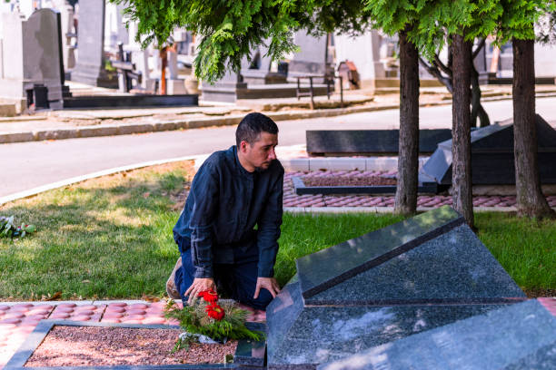 emotional gestresst mann in schwarzem kneeling vor grab seines verstorbenen freundes - spooky cemetery single flower flower stock-fotos und bilder