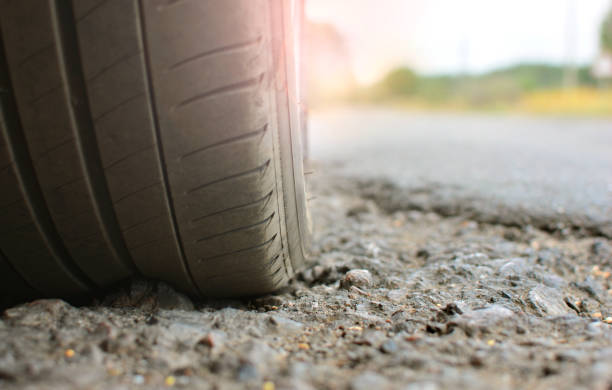 Closeup of automobile tire on a broken asphalt road Closeup of automobile tire on a broken asphalt road sinkhole stock pictures, royalty-free photos & images